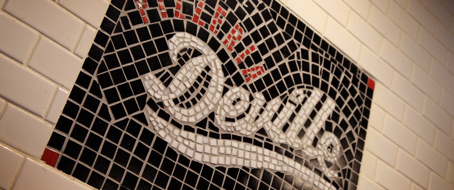 Pizzeria DeVille mosaic logo sign above the pizza oven.