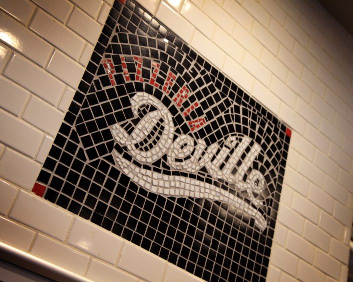 Pizzeria DeVille mosaic logo sign above the pizza oven.