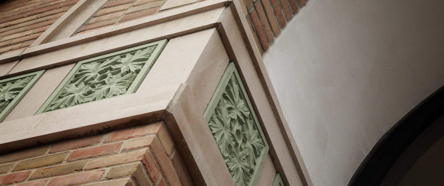 Exterior facade details of an oak leaf pattern in green stone suggesting growth, strength, and stability.
