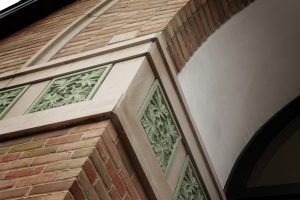 Exterior facade details of an oak leaf pattern in green stone suggesting growth, strength, and stability.